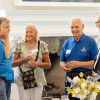Group of five standing by table and conversing with each other